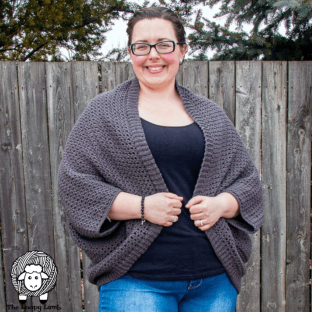 Woman smiling wearing a grey crochet cocoon cardigan.