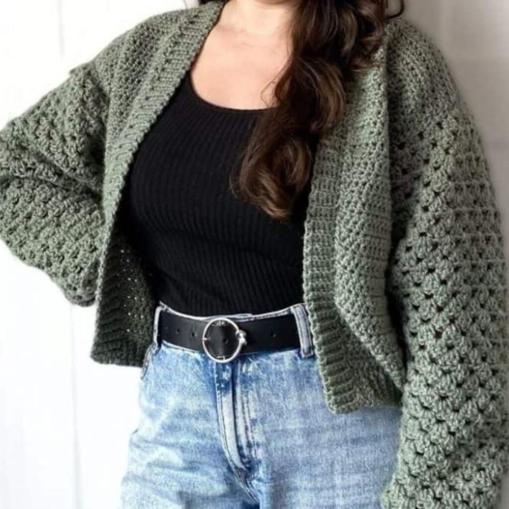 Person wearing a dark green granny stitch crochet cardigan.