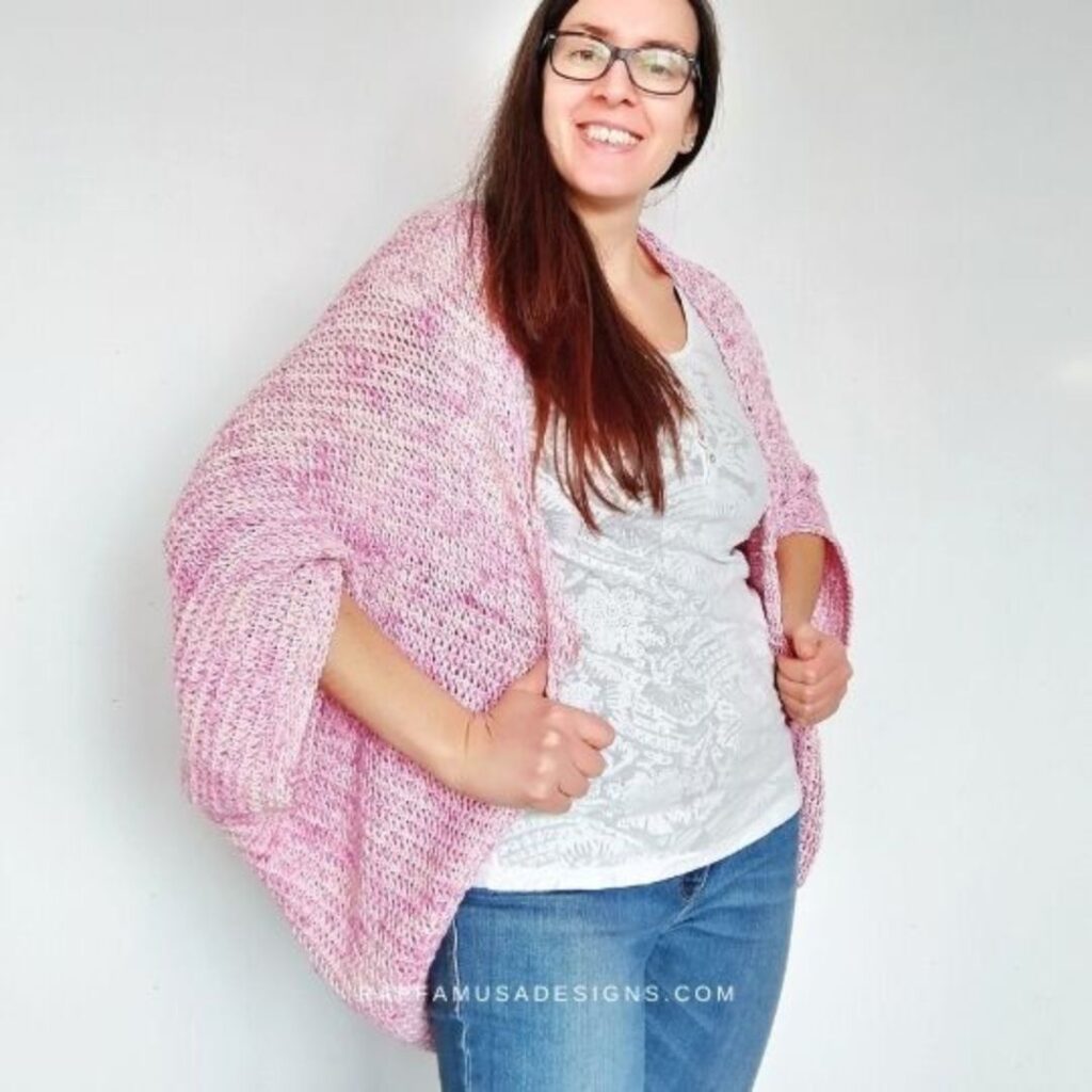 Woman wearing a pink Tunisian crochet shrug over her shoulders.