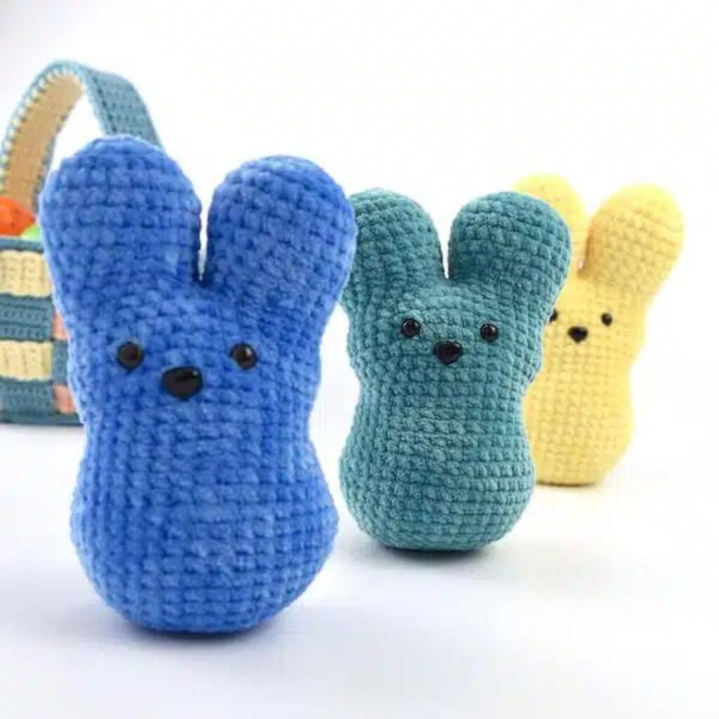 Three crochet peeps lined up in a row. From left to right they are blue, green, and yellow.