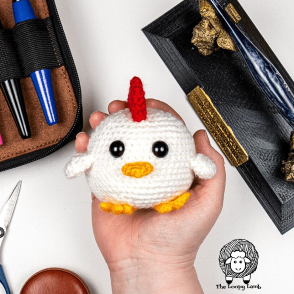 Small white crocheted chick held in the palm of a hand.